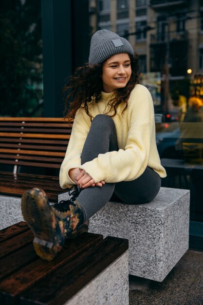 Charmante jonge krullende vrouw die op straat loopt