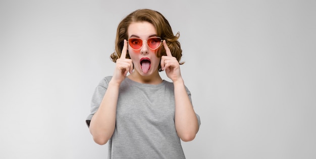 Charmante jonge vrouw in een grijs T-shirt. Gelukkige vrouw in rode glazen.