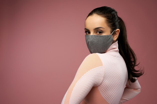 Charmante jonge vrouw in stoffen gezichtsmasker poseren in studio