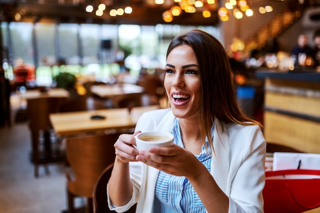 Charmante Kaukasische lachen brunette zitten in de cafetaria