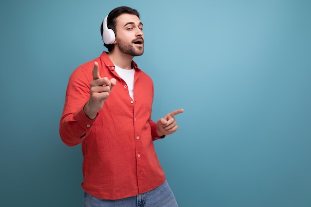 Charmante positieve man in rood shirt met draadloze witte koptelefoon