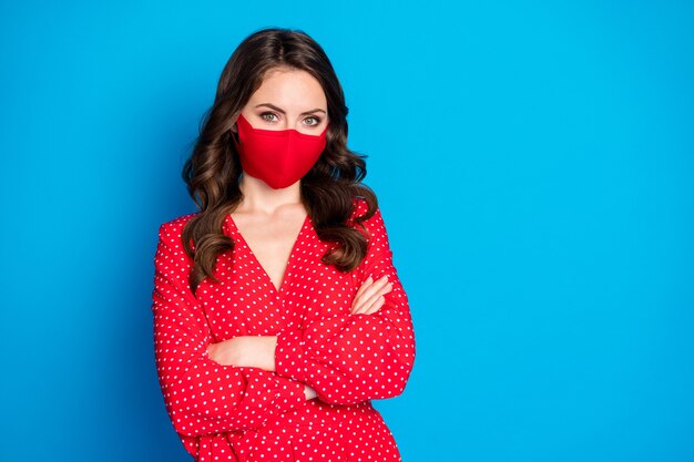 charmante verantwoordelijke brunette dame draagt een rood medisch masker met gekruiste armen