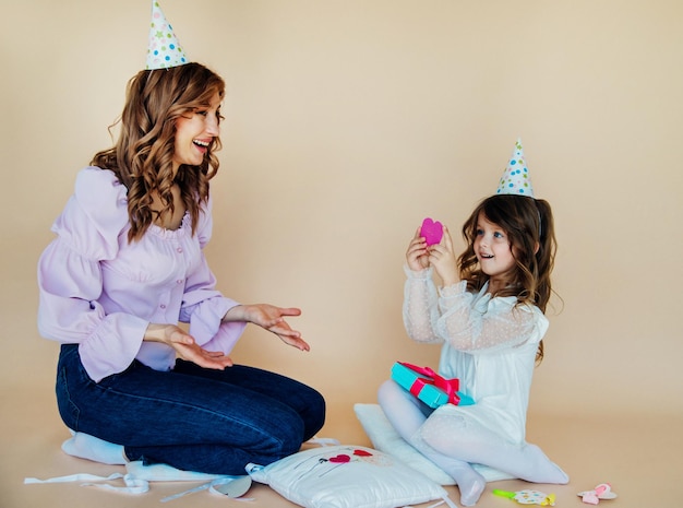 Charmante vrolijke familie zittend op de vloer en plezier hebben tijdens de feestelijke tijd Verjaardagsconcept Moeder en dochter feliciteren elkaar