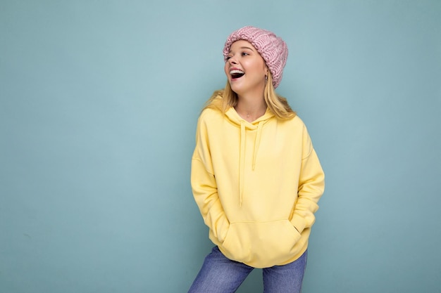 Charmante vrolijke positieve gelukkige jonge blonde vrouw geïsoleerd over kleurrijke achtergrond muur dragen casual stijlvolle kleding gevoel oprechte emoties op zoek naar de kant. lege ruimte