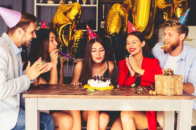 Charmante vrouw blaast op kaarsjes op de verjaardagstaart na het maken van haar wens op feestje