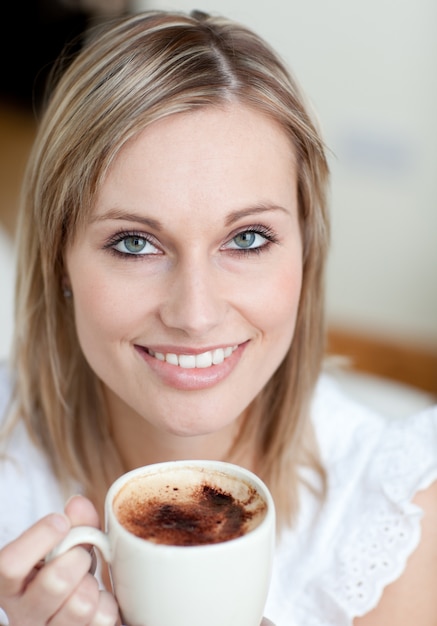 Charmante vrouw die een koffiezitting op een bank drinkt