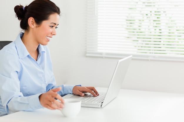 Charmante vrouw die met haar laptop ontspannen terwijl het genieten van een van koffie