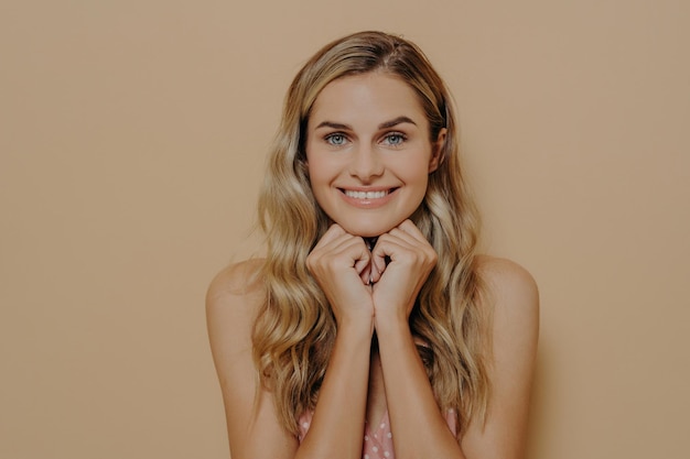 Charmante vrouw in zomerjurk handen onder kin stralende glimlach perfect haar gelukkige uitdrukking