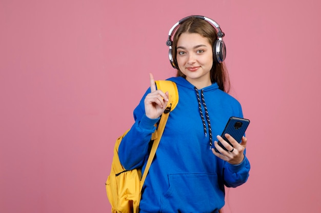 Charmante vrouw met een draadloze koptelefoon die met de wijsvinger gebaart terwijl ze naar muziek luistert