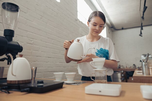 Charmante vrouwelijke barista die filterkoffie maakt in cafetaria