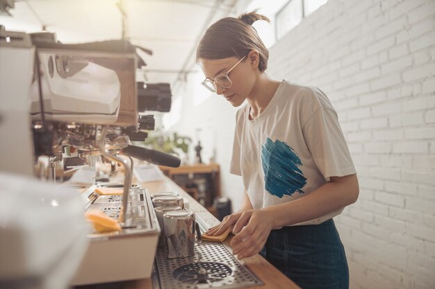 Charmante vrouwelijke barista-schoonmaakbalie in coffeeshop