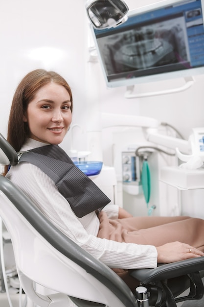 Charmante vrouwelijke patiënt lachend naar de voorkant te wachten op tandheelkundige afspraak in de kliniek