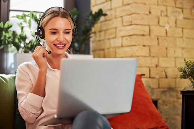 Foto charmante zakenvrouw in koptelefoon praten met zakenpartner op laptop