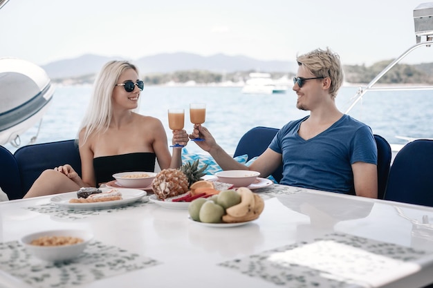 Charming adult couple man and woman are having dinner at the table of their huge and expensive white