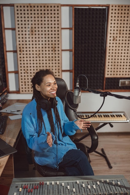 Charming african woman radio presenter talks into microphone while broadcasting interesting program