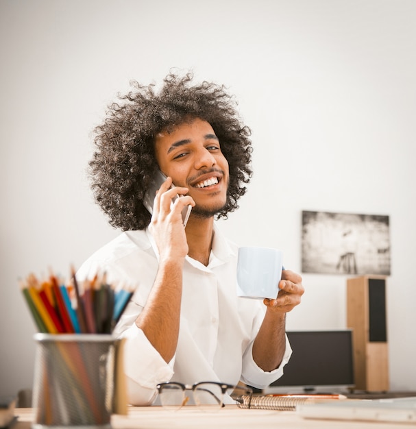 Charming Arab guy toothy smiles talking on smartphone.