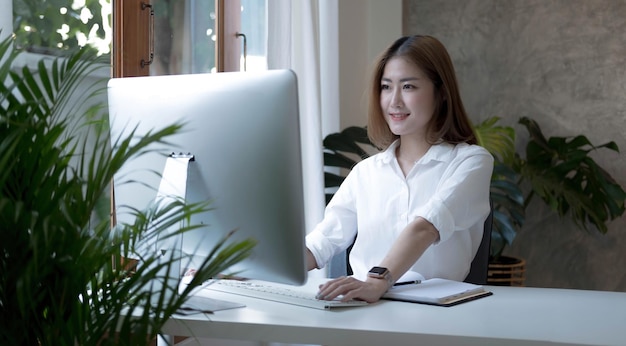 Charming asian businesswoman sitting working on laptop in office