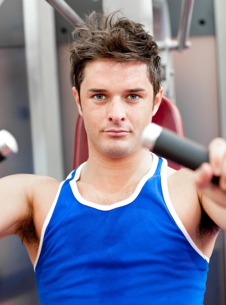 Charming athletic man using a bench press