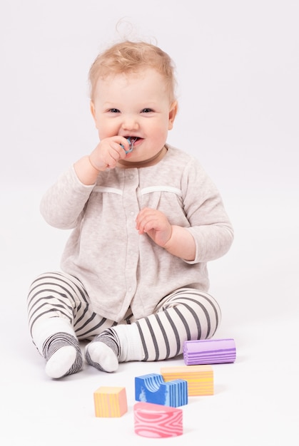 Charming baby plays with toys on the white floor