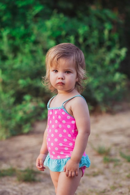 Photo charming baby in swimsuit by the river