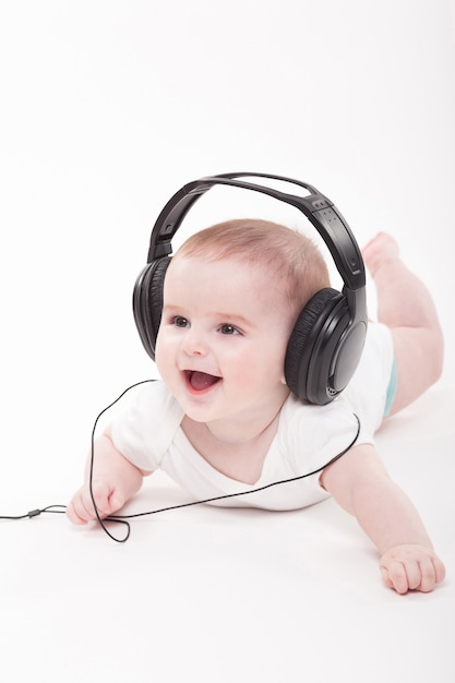 Charming baby on a white background with headphones listening to