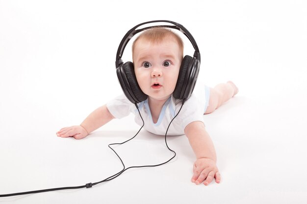 Charming baby with headphones listening to