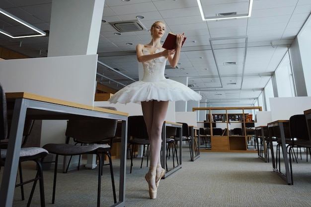 Charming ballerina went to the library to choose a new book during a break showing your stretching and flexibility