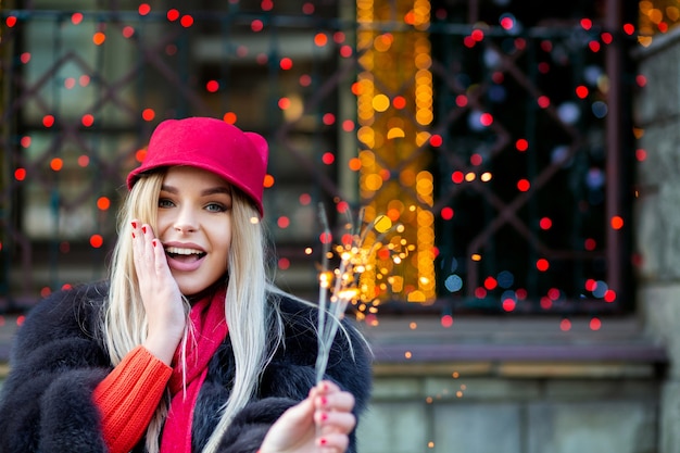 Affascinante modella bionda che celebra il nuovo anno con le stelle filanti alle luci sfocate della città. spazio per il testo