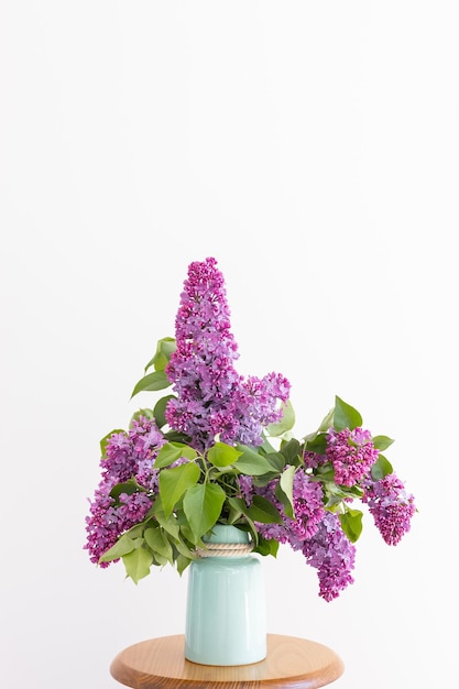 Charming bouquet of blooming lilac in vase on grey