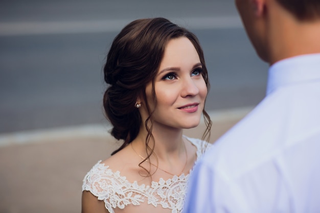 Charming bride looks at groom with love.