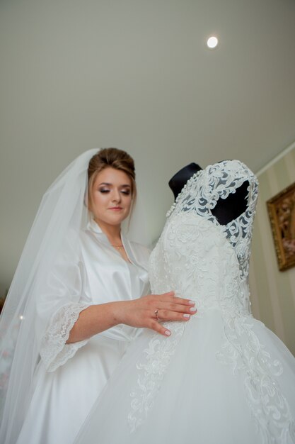 신부 들러리가있는 매력적인 신부가 웨딩 드레스 근처에 서 있습니다.