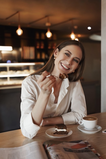 Charming business woman eating a delicious dessert and smiling.