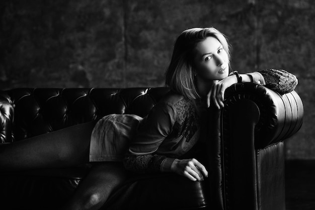 A charming characteristic blonde in a denim suit posing sitting in an armchair