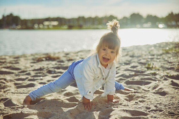 Charming child playing on the beach at sunset