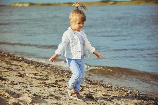 Charming child walking on the beach at sunset