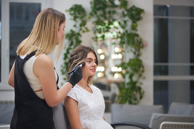 Photo charming client getting professional makeup in beauty salon