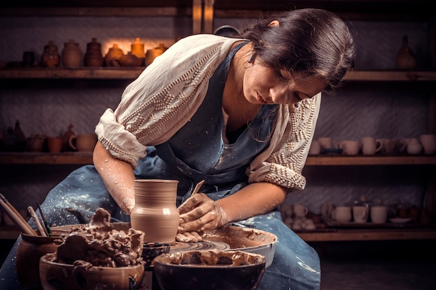 Charming craftsman master working on potters wheel with raw clay with hands