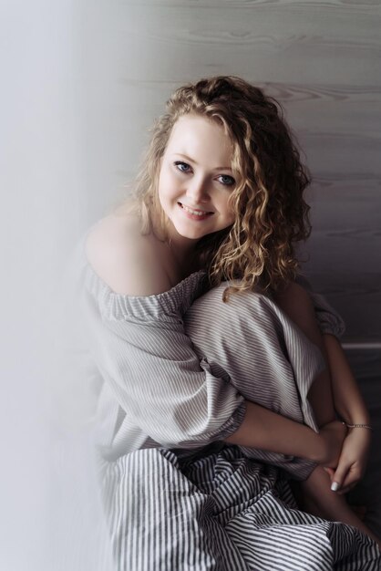 Charming curly-haired woman in beautiful dress resting, looking at camera and smiling