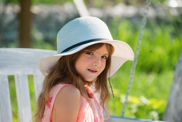 Charming cute caucasian little girl wearing straw hat standing outdoors funny kids face happy child