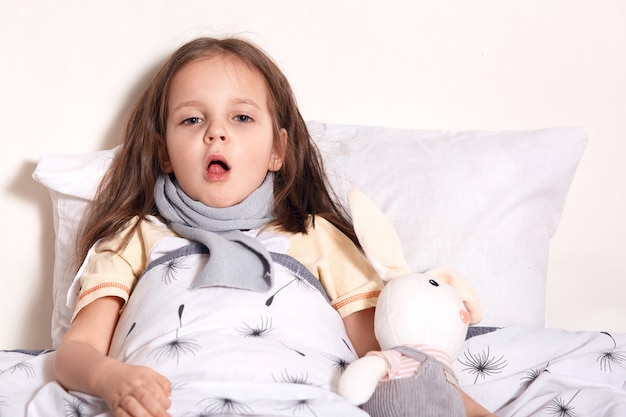 Charming cute child lying in her bed with toy