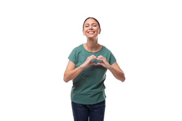 Foto affascinante carina amichevole sottile giovane donna brunetta vestita con una maglietta verde sorridendo su un bianco