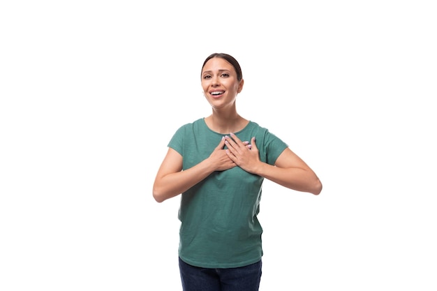 Foto affascinante carina amichevole sottile giovane donna bruna vestita con una maglietta verde sorridendo su un bianco