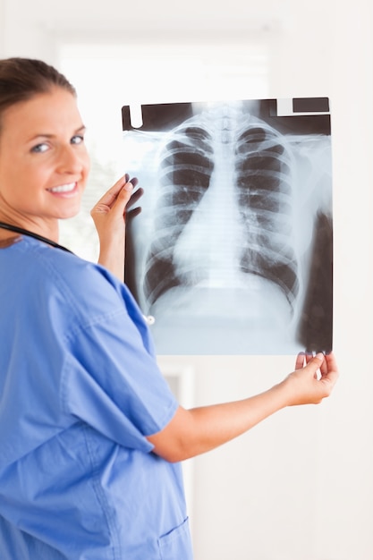 Charming doctor smiling at the camera holding a x-ray