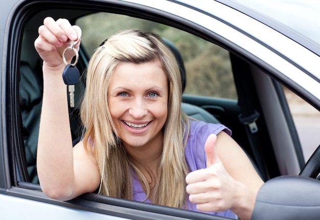 Autista femminile affascinante che mostra una chiave dopo l'acquisto di una nuova auto