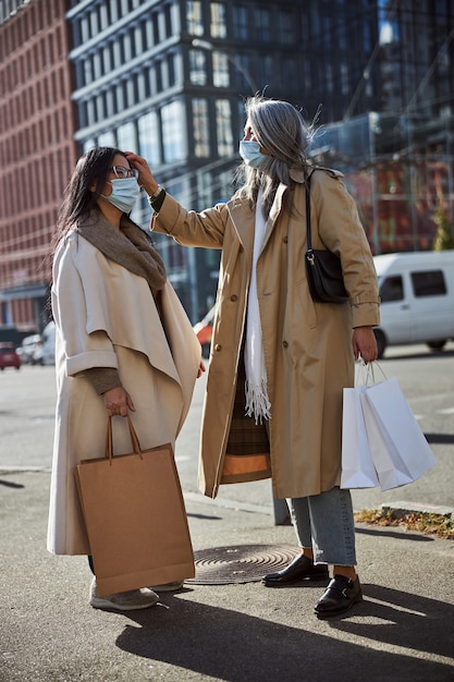 通りに立っている医療マスクの魅力的な女性の友人