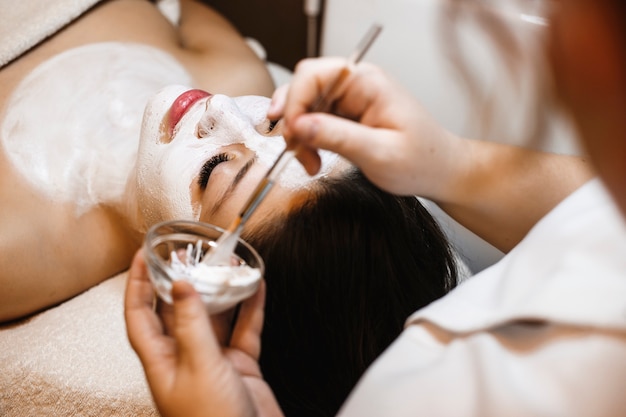 Charming female relaxing after work in a wellness spa doing facial procedures.