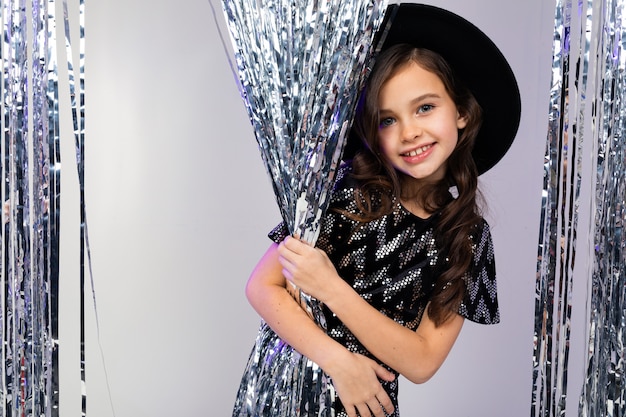 Charming girl in a black hat and elegant dress posing on a birthday in the studio