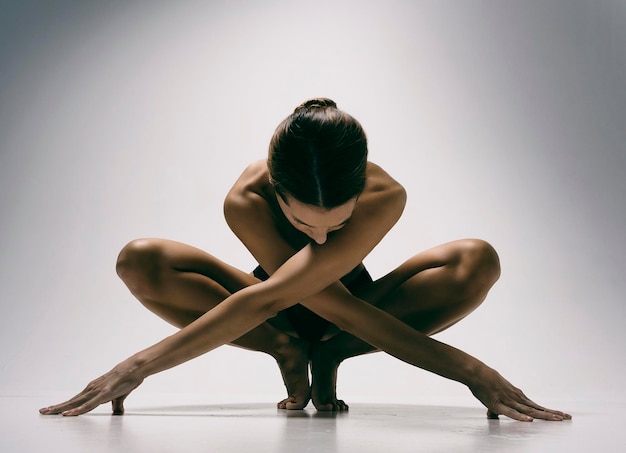 a charming girl demonstrates stretching and yoga asanas in a photo studio