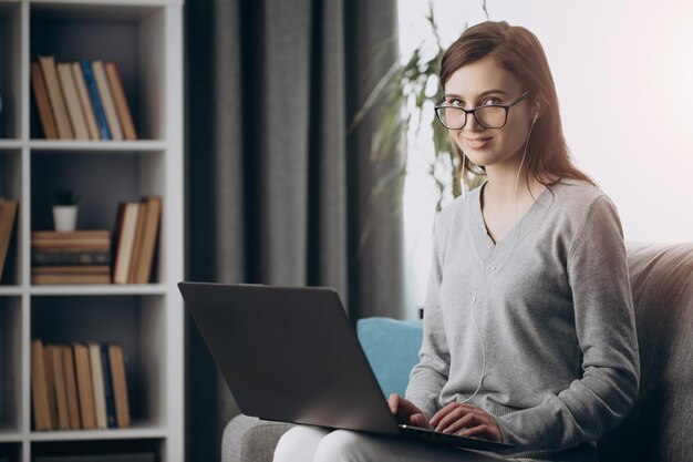 노트북으로 자유 시간을 보내는 안경을 쓴 매력적인 소녀
