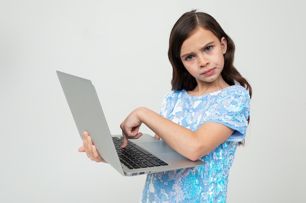 Charming girl made an order for an educational course via the Internet using a laptop on a white